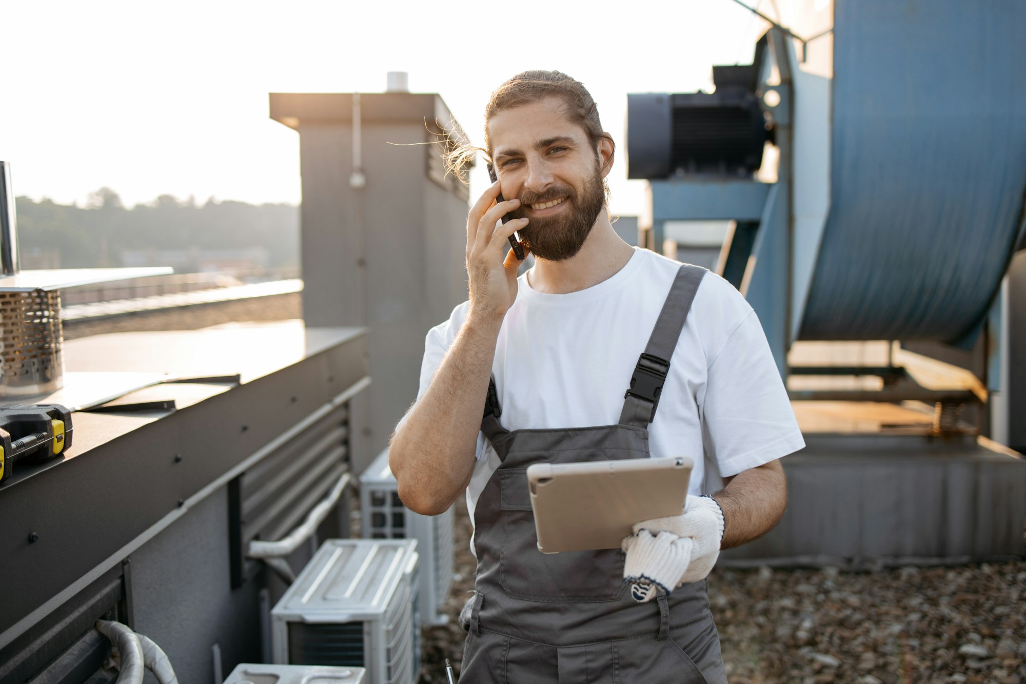 Man engineer talking on mobile and holding tablet on roof